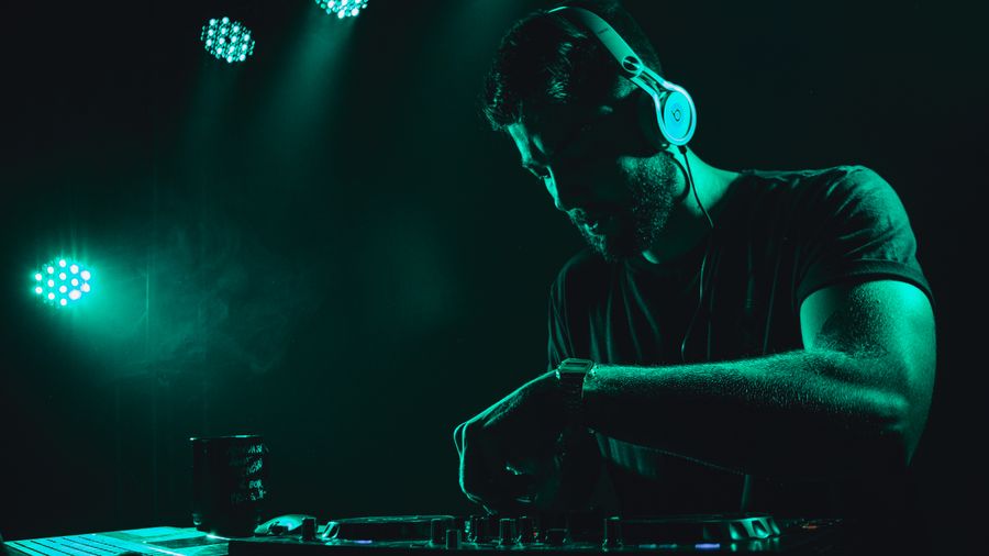 DJ mixing music live on stage with vibrant lighting