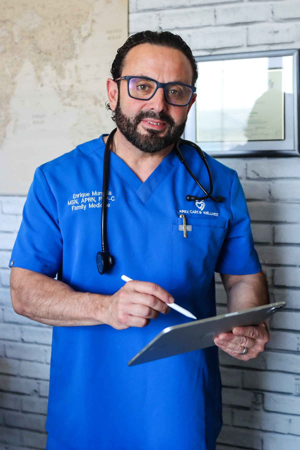 Enrique Murguia, FNP-C reviewing clinical tablet records at Apex Care & Wellness