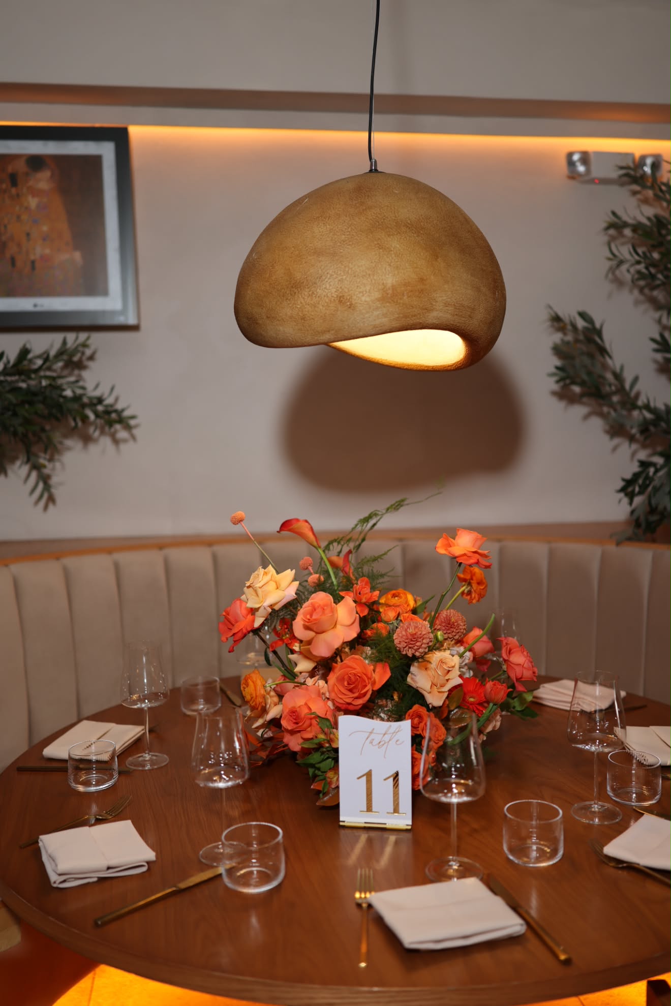 Sunset orange and peach floral centerpiece with sculpted pendant lighting and custom table number 11