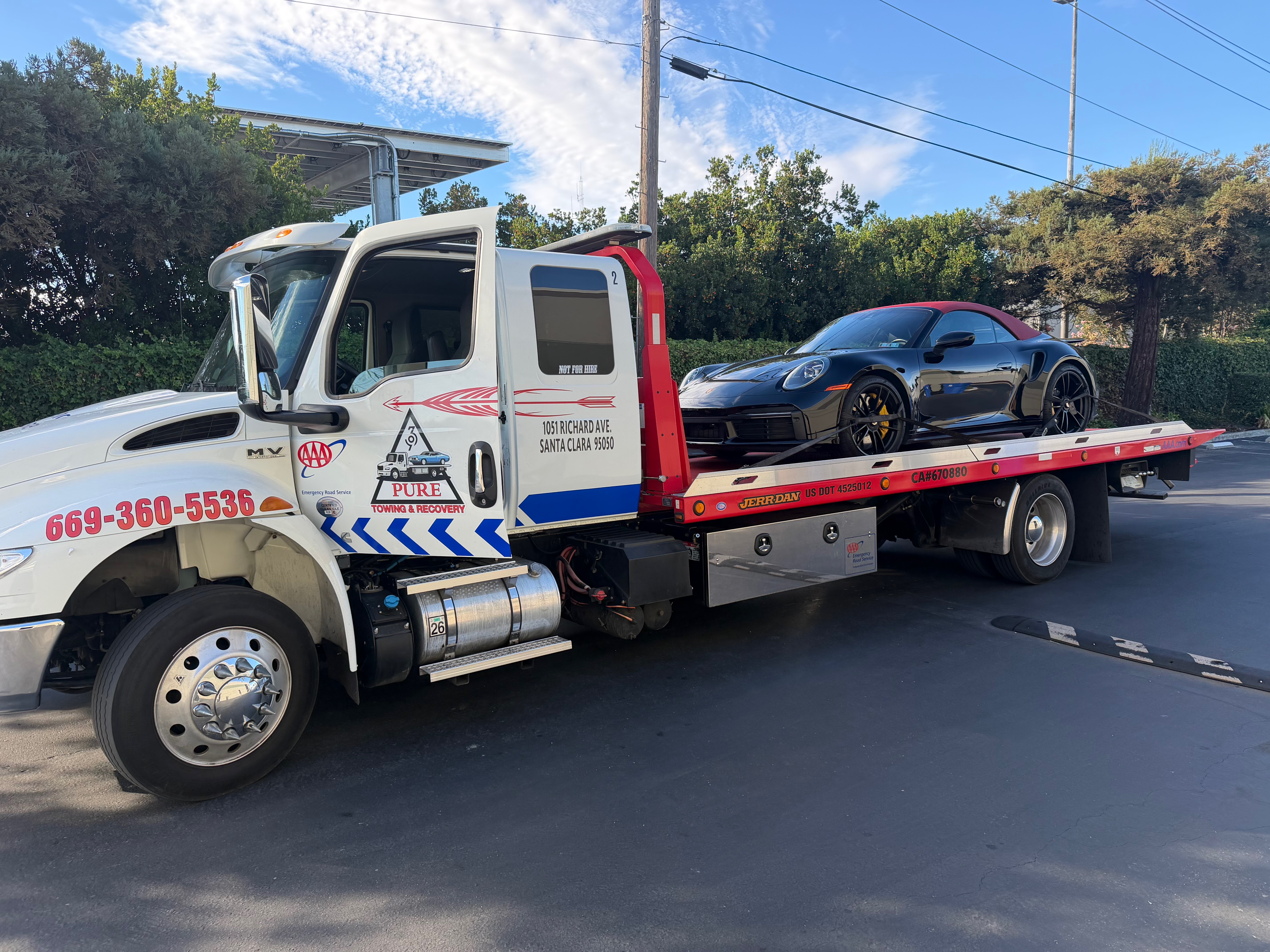 Pure Towing heavy-duty rollback flatbed safely transporting a black Porsche 911 Turbo convertible with red soft top