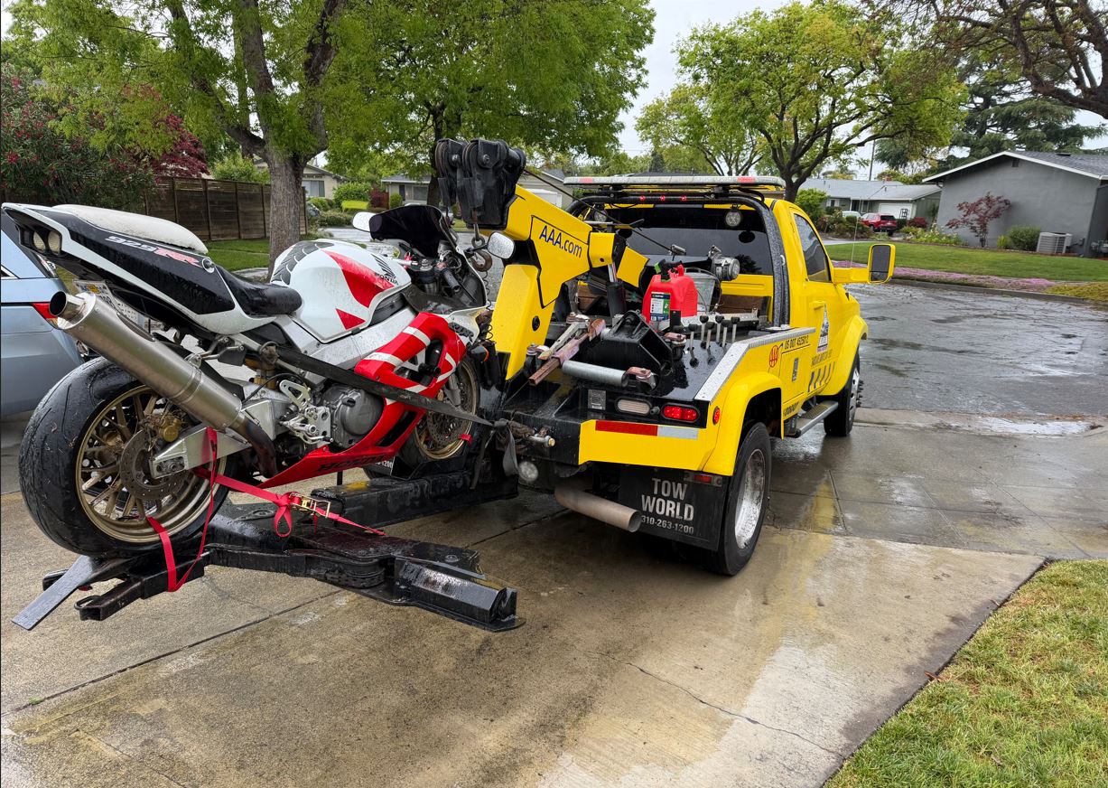 Pure Towing service truck safely carrying a red and white Honda 929RR motorcycle using a specialized rear transport cradle and heavy-duty straps
