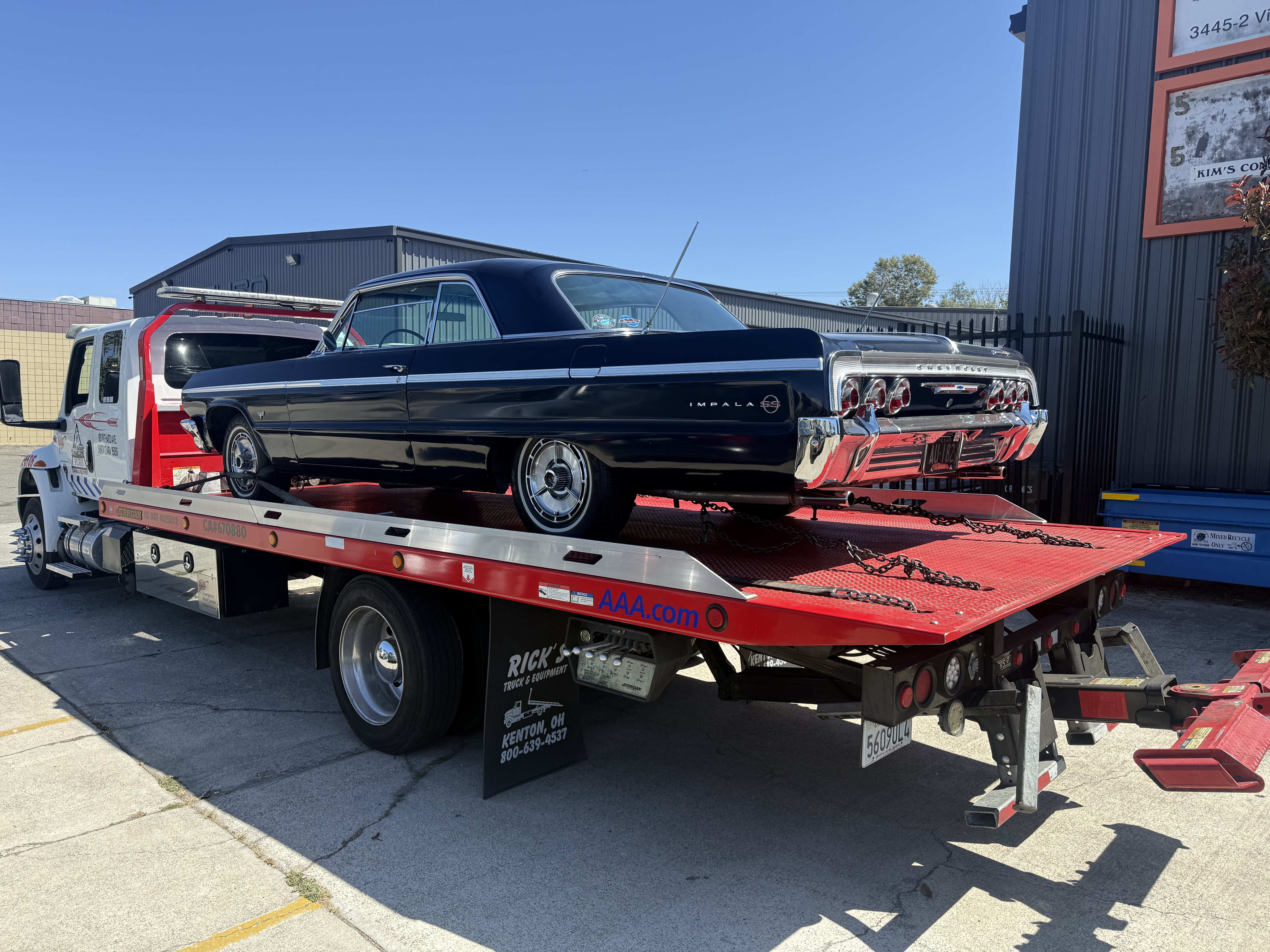 Pure Towing & Recovery commercial rollback flatbed tow truck loaded with classic 1964 Chevy Impala SS in Santa Clara