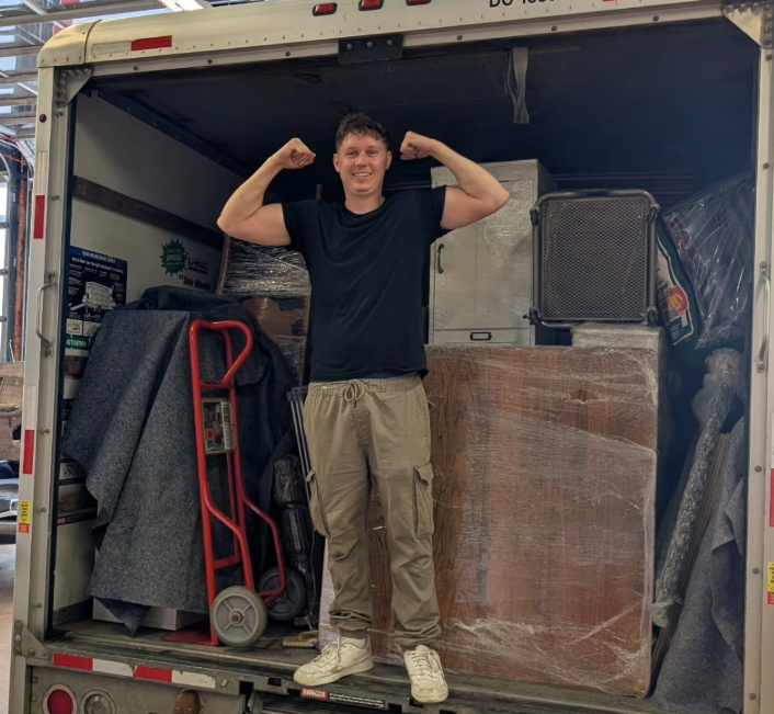 Mathieu standing in the back of a loaded moving truck