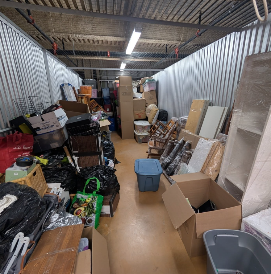Storage unit full of boxes, bags and furniture before cleanout