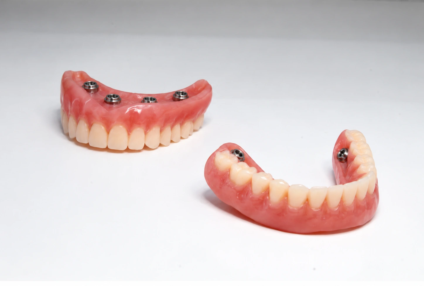 Implant-retained dentures with locator abutment housings displayed on a white surface