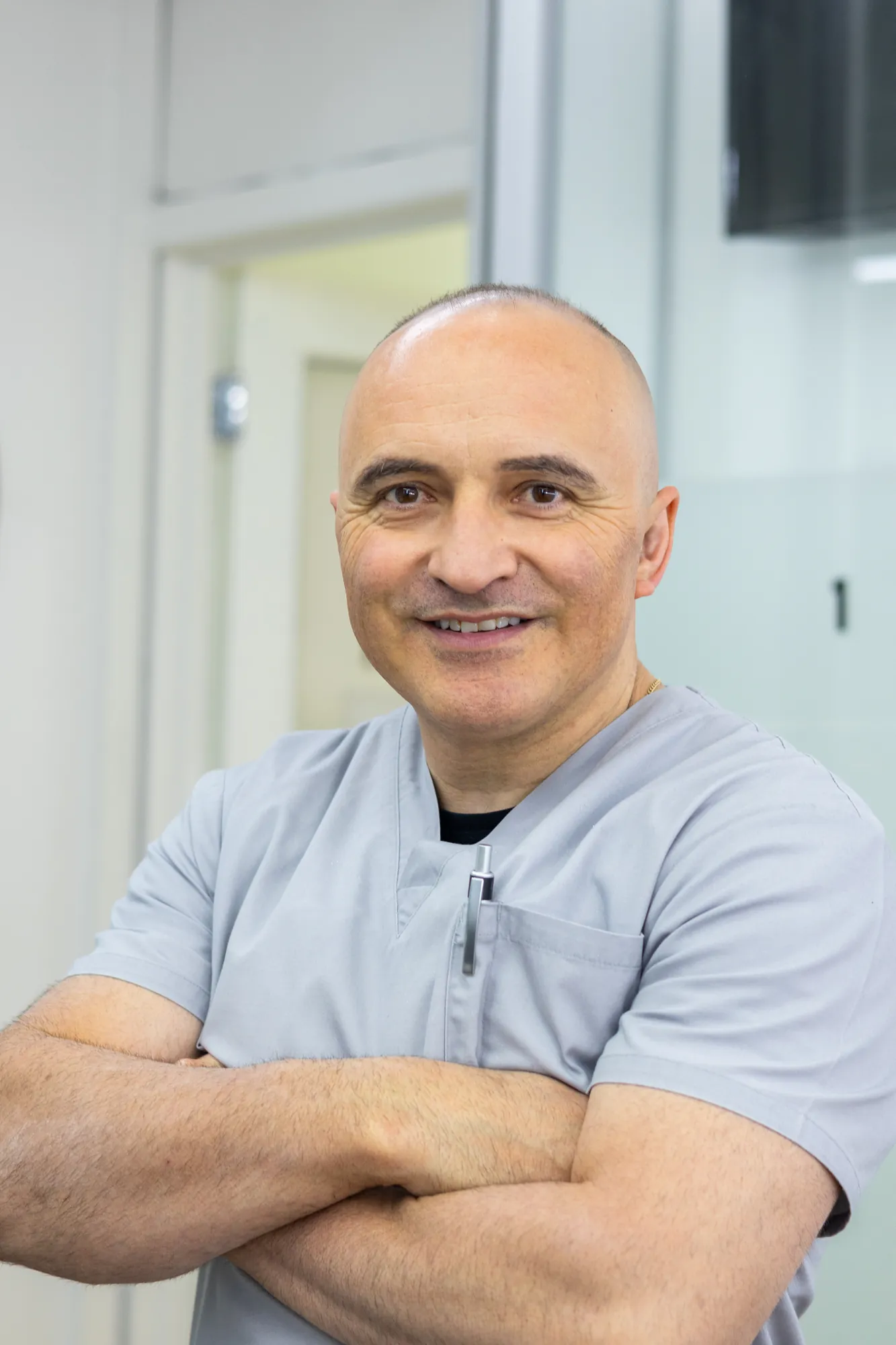 Dental prosthetist Dr Dragan Flajnik smiling with arms crossed at Preston Dentures clinic