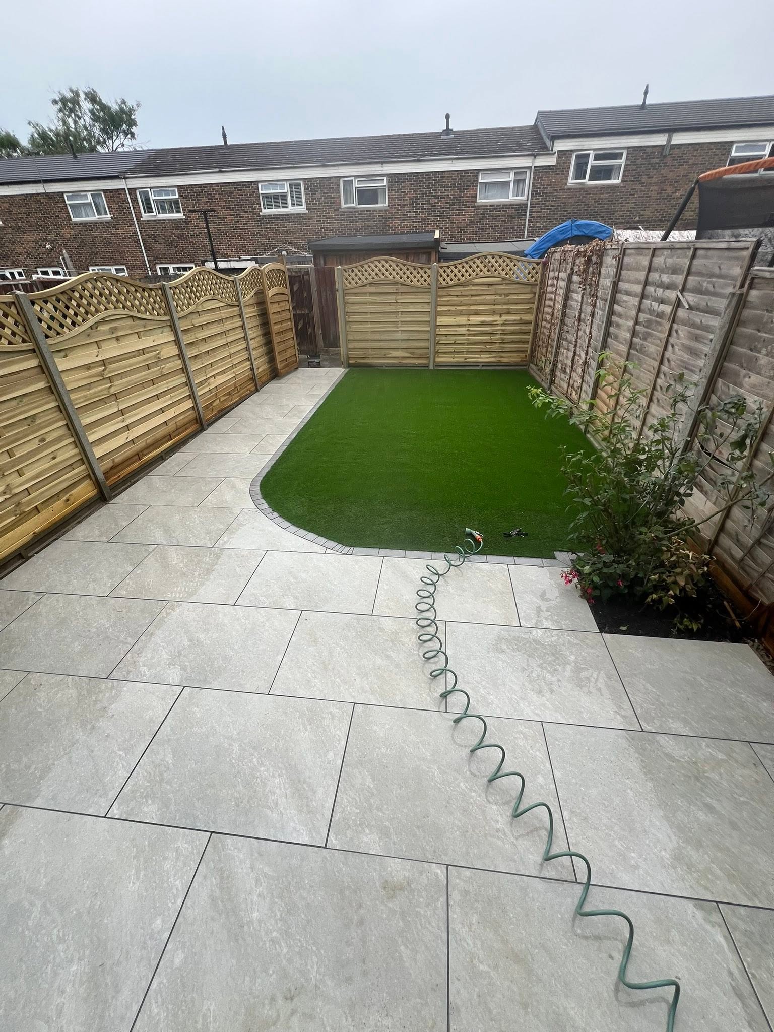 Clean porcelain patio paving with lawn integration and fencing