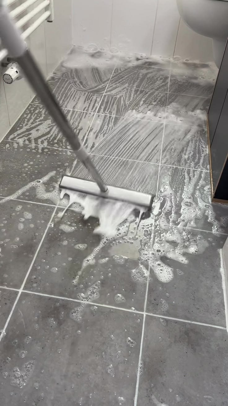 Professional floor squeegee scrub with dense sanitizing foam on grey tile floor by Lorena García Cleaning Services LLC