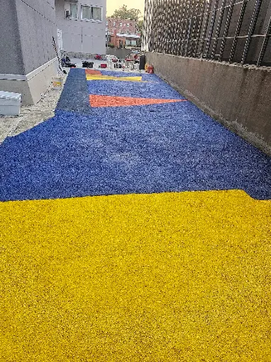 Hudson Epoxy Flooring completed colorful outdoor concrete coating with bold blue, yellow, and orange geometric color blocking along building courtyard walkway