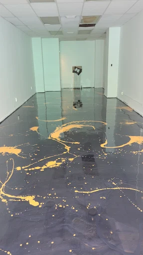 Hudson Epoxy Flooring completed dark commercial floor with artistic gold accent splash across the open room
