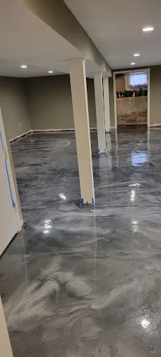 Hudson Epoxy Flooring completed gray metallic high-gloss floor coating across finished basement with structural support columns and recessed lighting