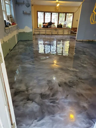 Hudson Epoxy Flooring completed wide living area with high-gloss gray and silver metallic epoxy floor reflecting exterior window light