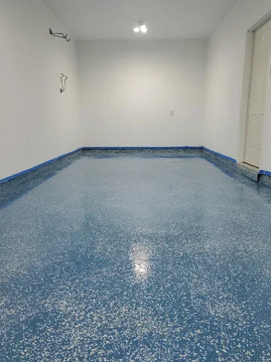 Hudson Epoxy Flooring completed vibrant blue decorative flake floor with white accents and blue taped perimeter during installation