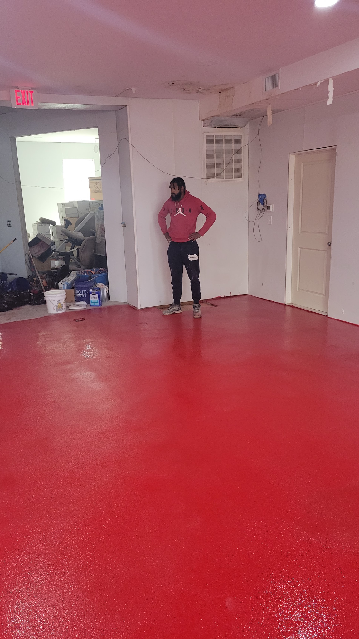 Hudson Epoxy Flooring installer inspecting freshly completed vibrant red coated floor in a commercial facility