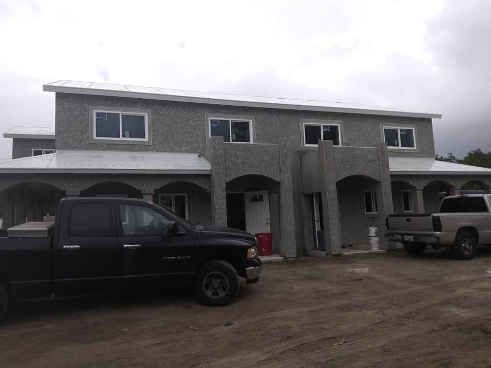 Front elevation of multi-family property with arched entryways and fresh exterior stucco prep in Naples