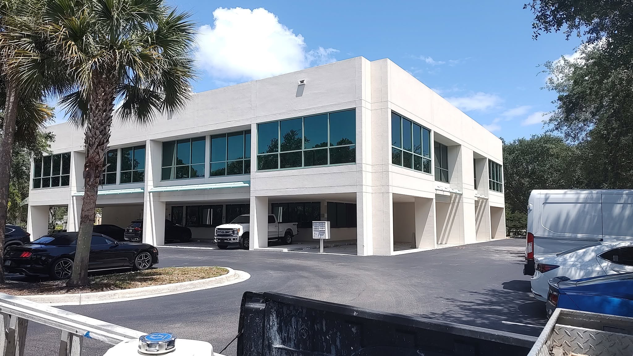 Two-story commercial office building in Naples with fresh off-white stucco coating and clean parking structure line