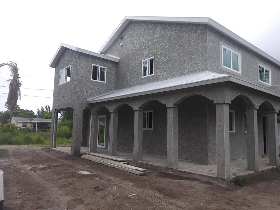 Two-story coastal multi-family building with newly applied stucco finish and arched columns in Naples