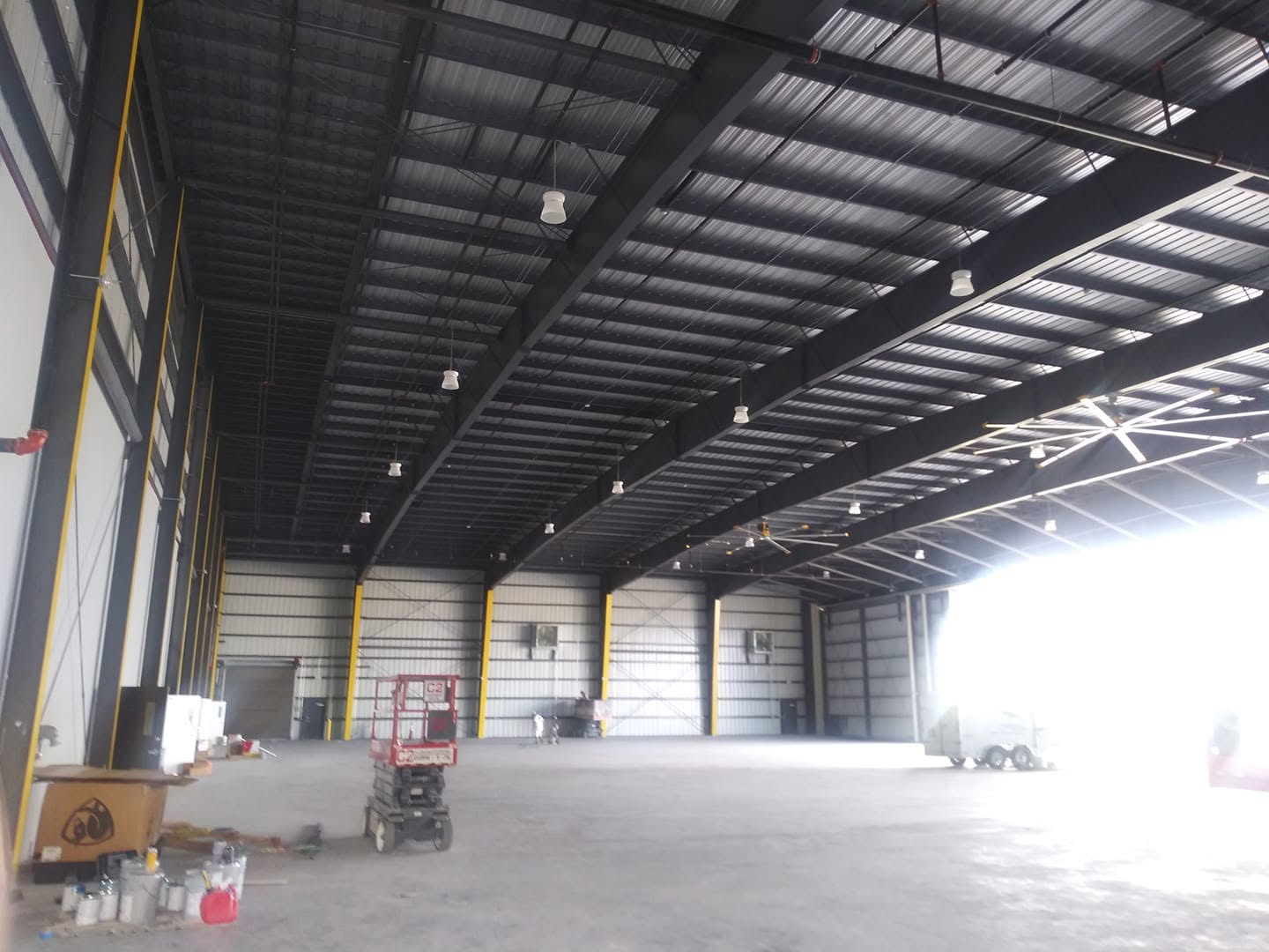 Commercial warehouse interior steel trusses and ceiling painted with scissor lift in Naples