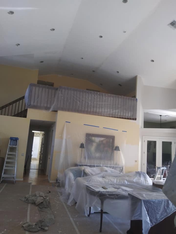 High-ceiling living room and second-floor mezzanine masked with protective plastic sheeting in Naples