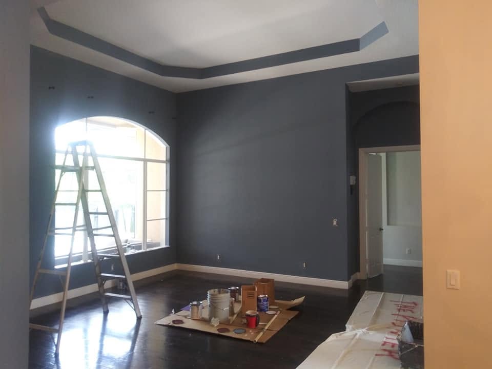 Finished deep-slate great room with contrasting white tray ceiling, arched window, and protected floors in Naples