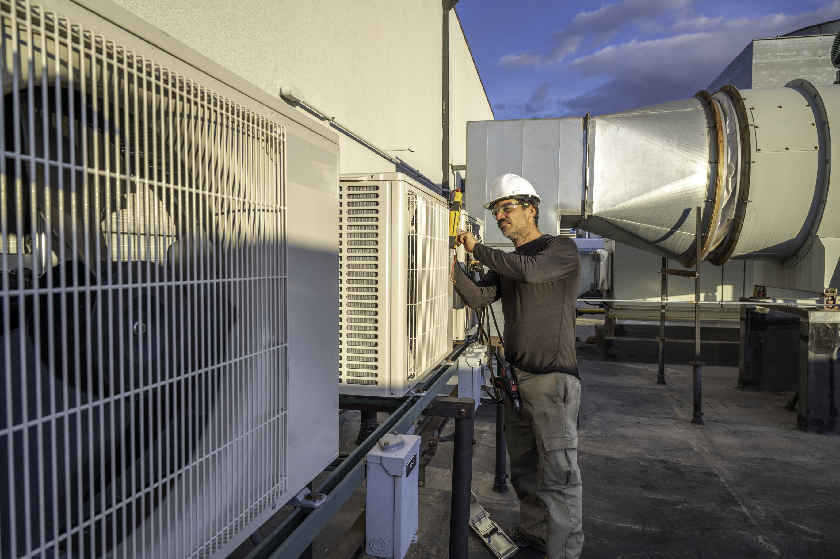 Technician servicing commercial rooftop HVAC unit