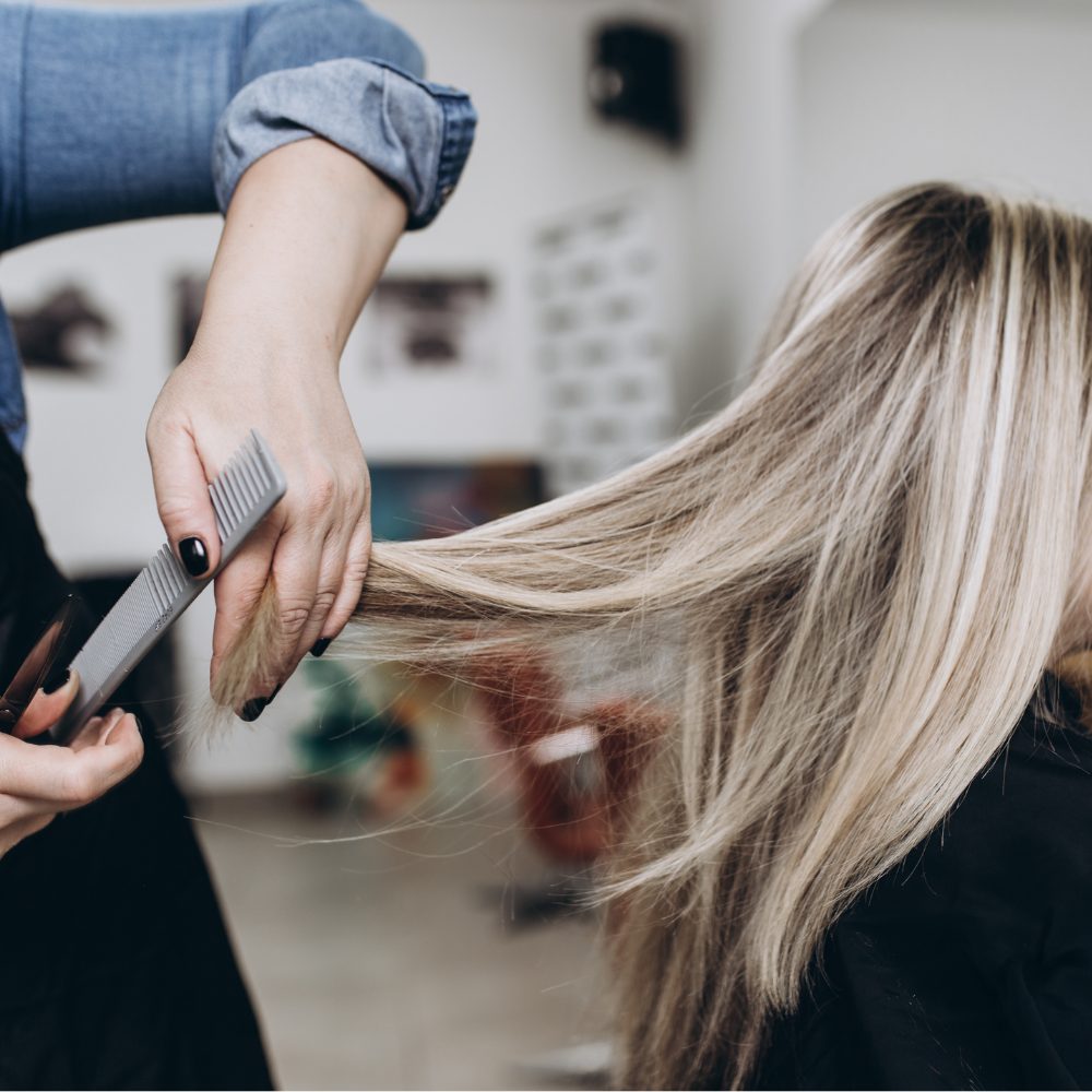 Hair stylist trimming a client's hair in a salon