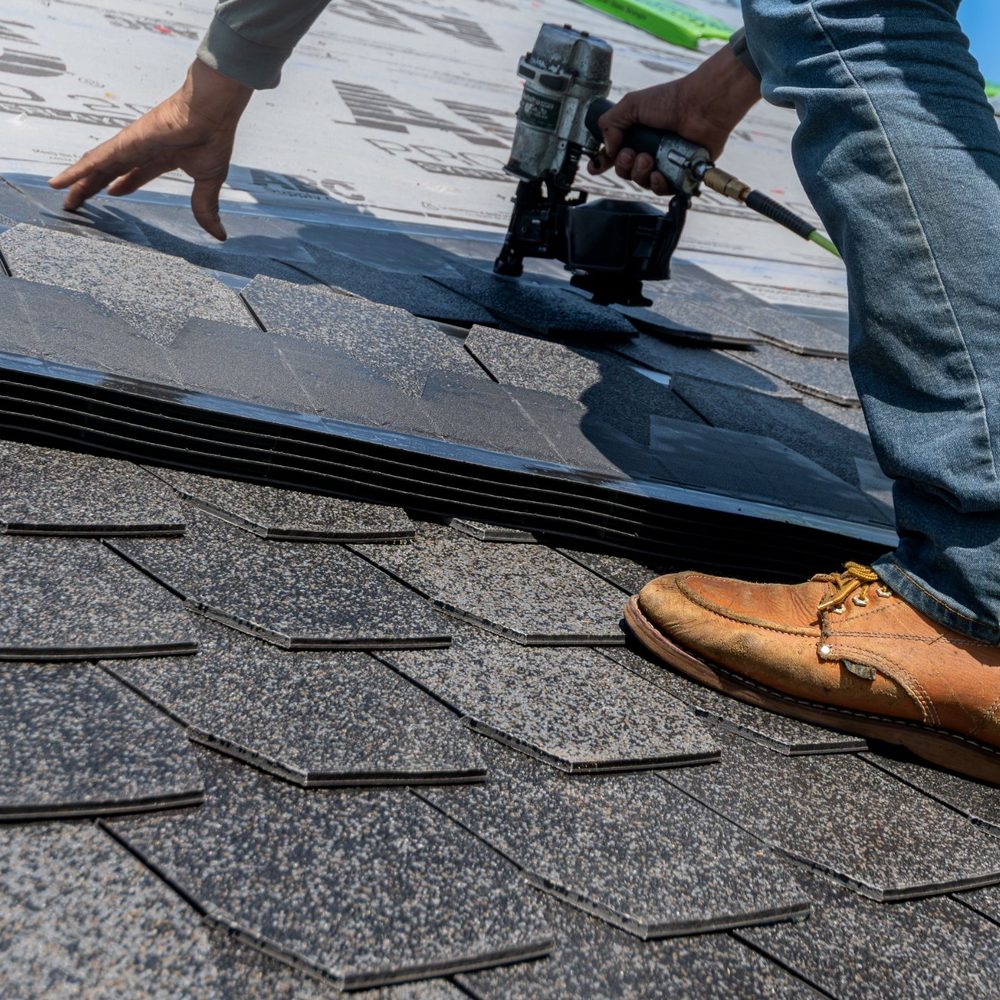 Roofer installing shingles with a nail gun