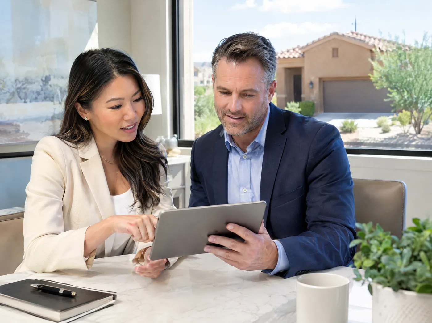 A real estate agent and a colleague reviewing a property file together on a tablet.