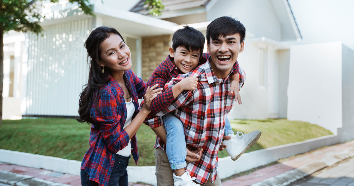 Happy Filipino parents giving their son a piggyback outside their family home