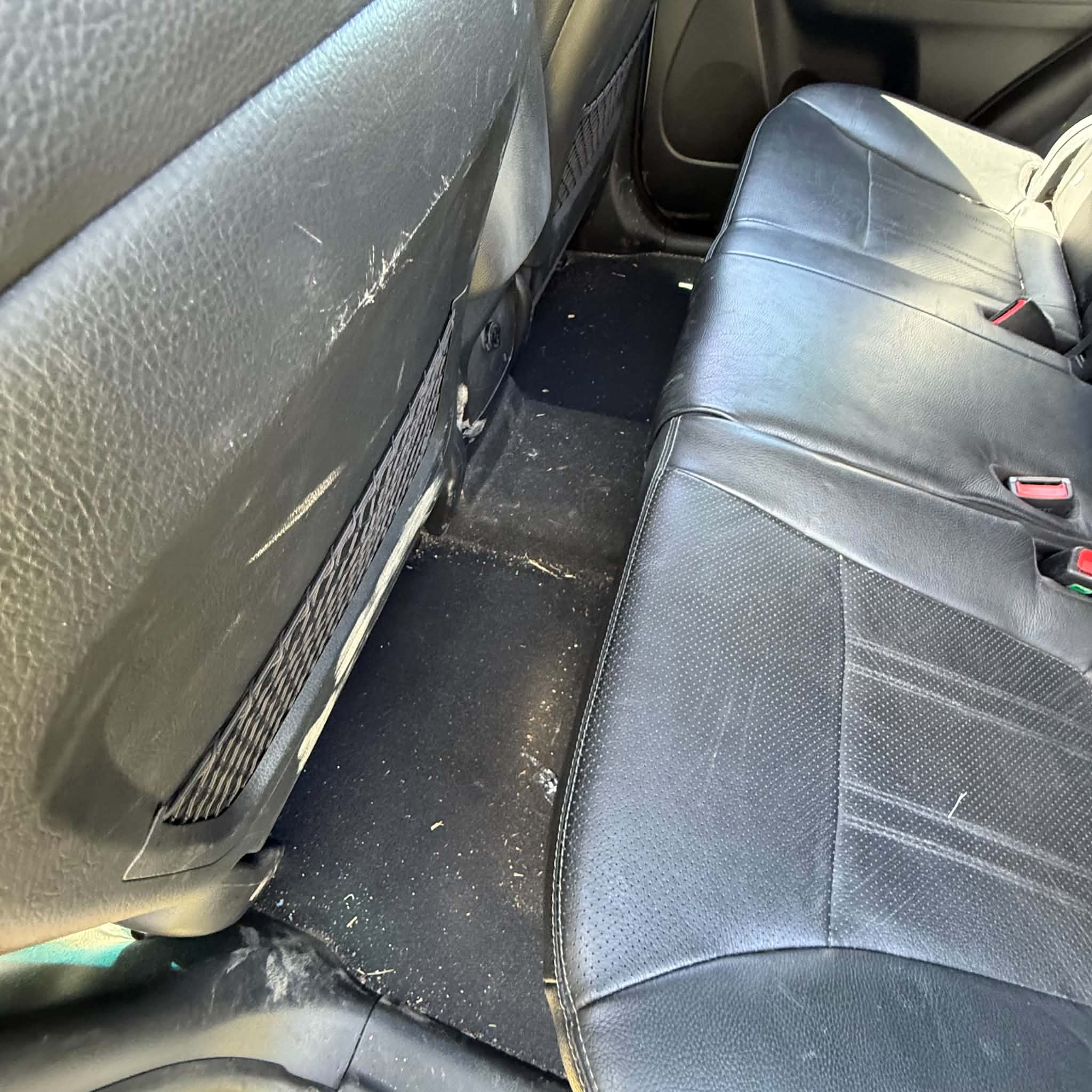 Car interior before detailing — back seat and floor carpet covered in dust, crumbs and dirt prior to a Maitland mobile car detail