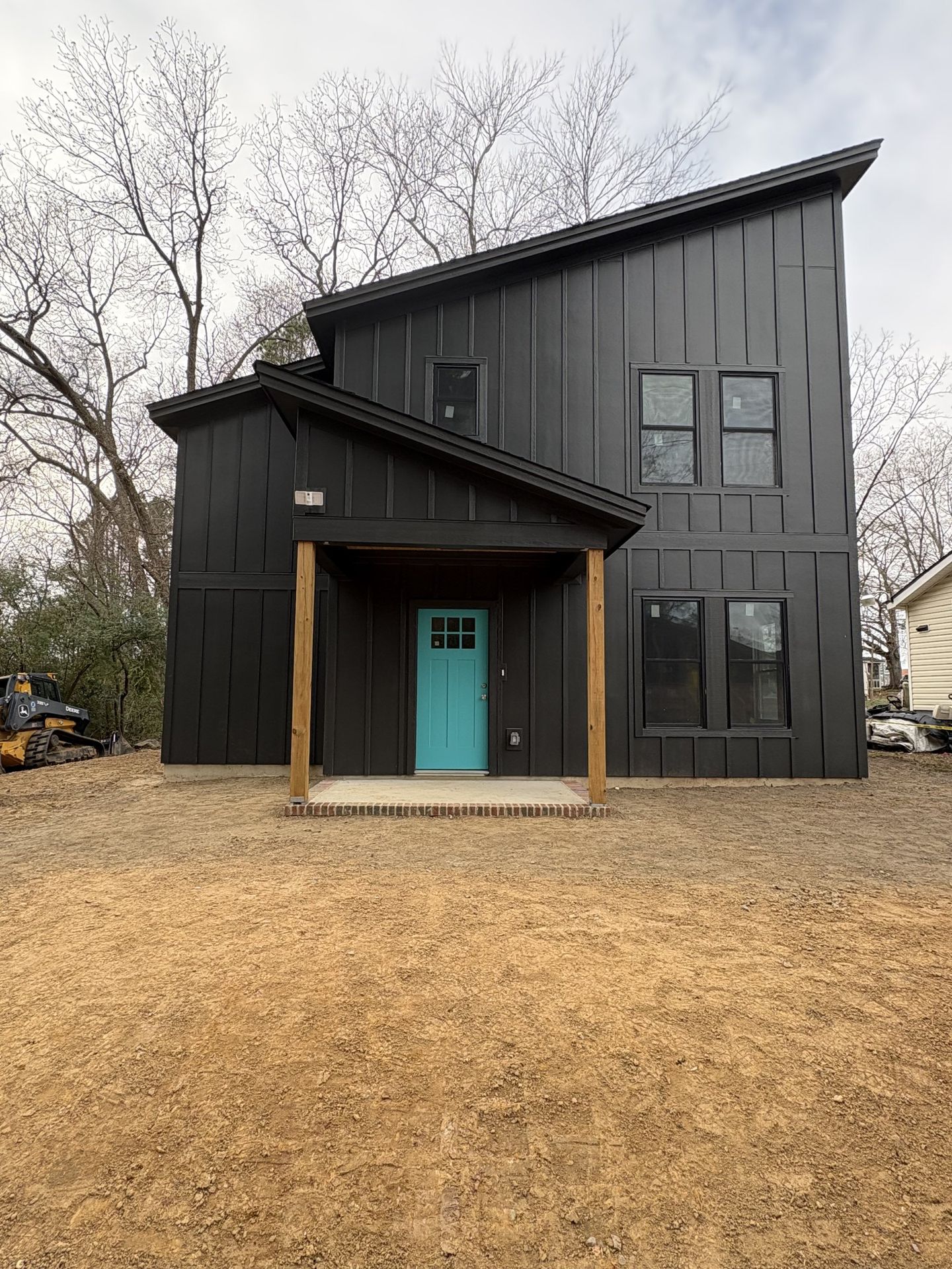 Modern exterior with black board and batten siding and a teal front door