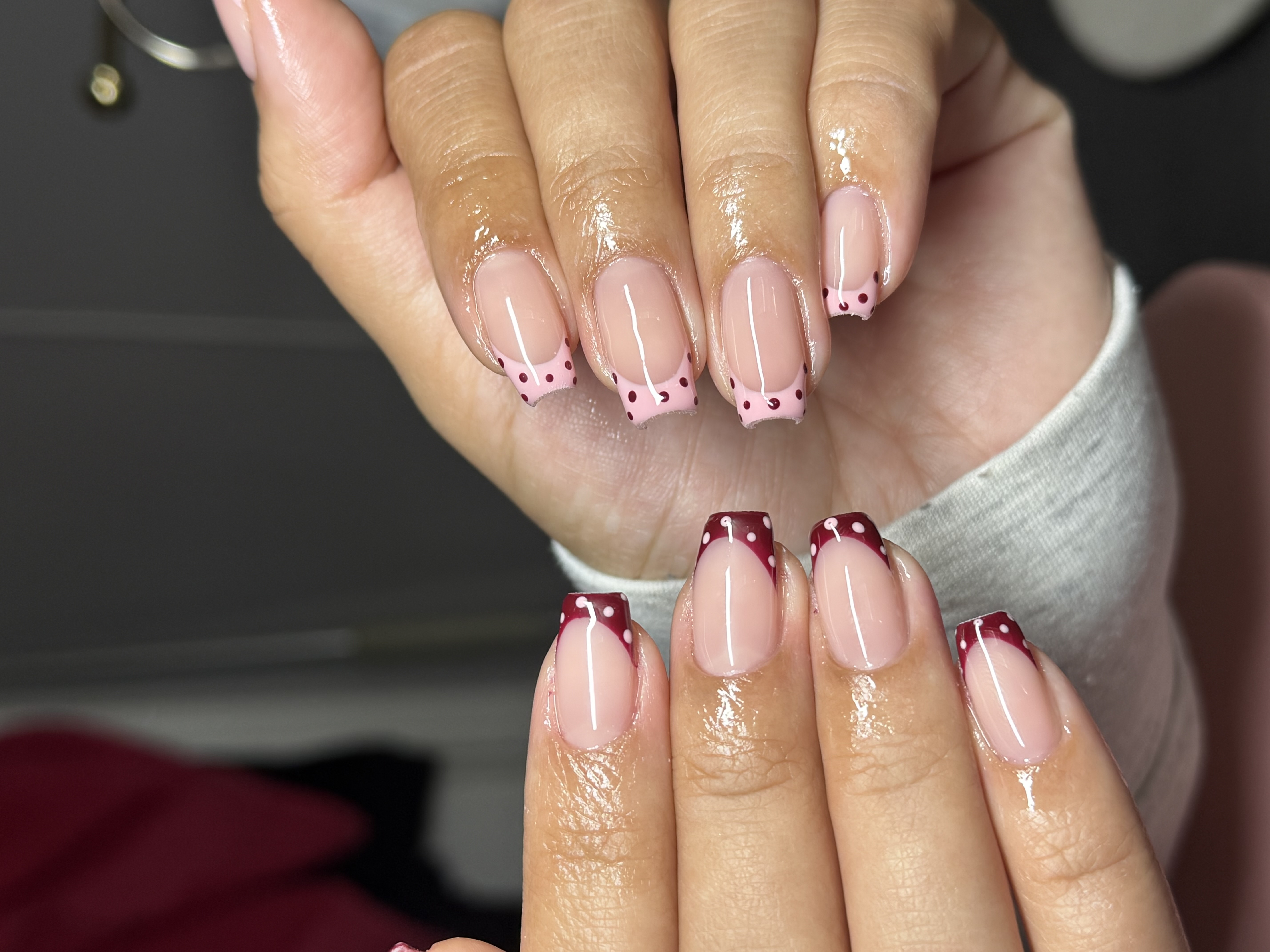 Dual hand square french tips featuring baby pink polka dot tips on one hand and deep burgundy wine tips with white polka dots on the other