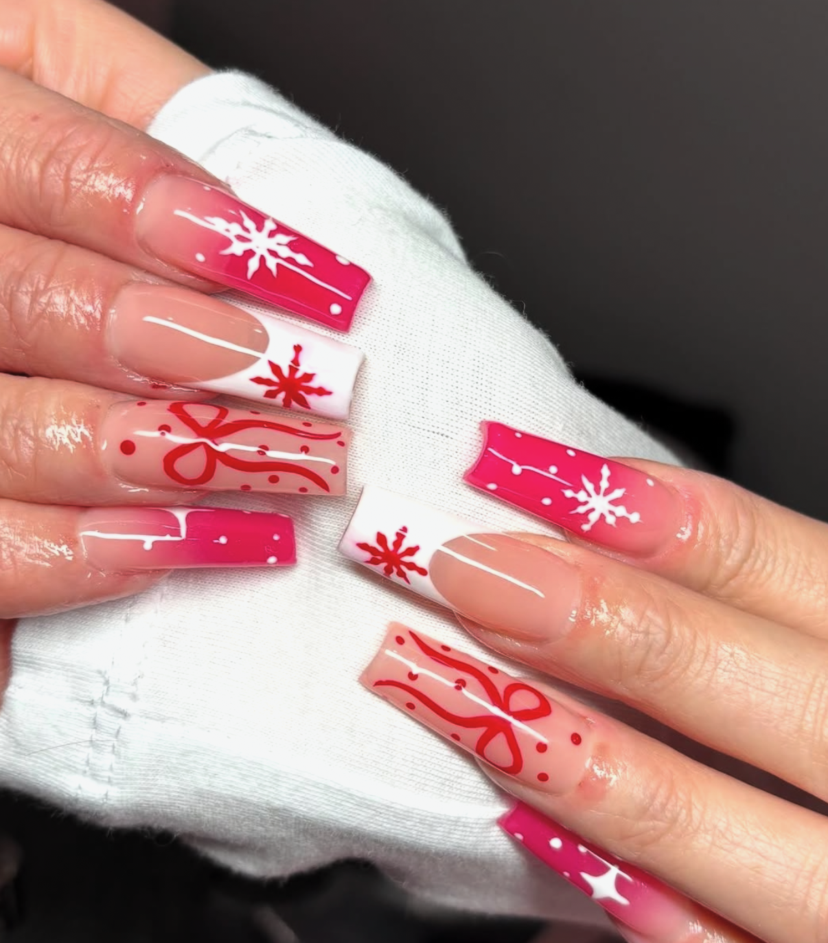 Long square nails with pink ombre snowflakes, white french tips, and hand-painted gift wrap bows