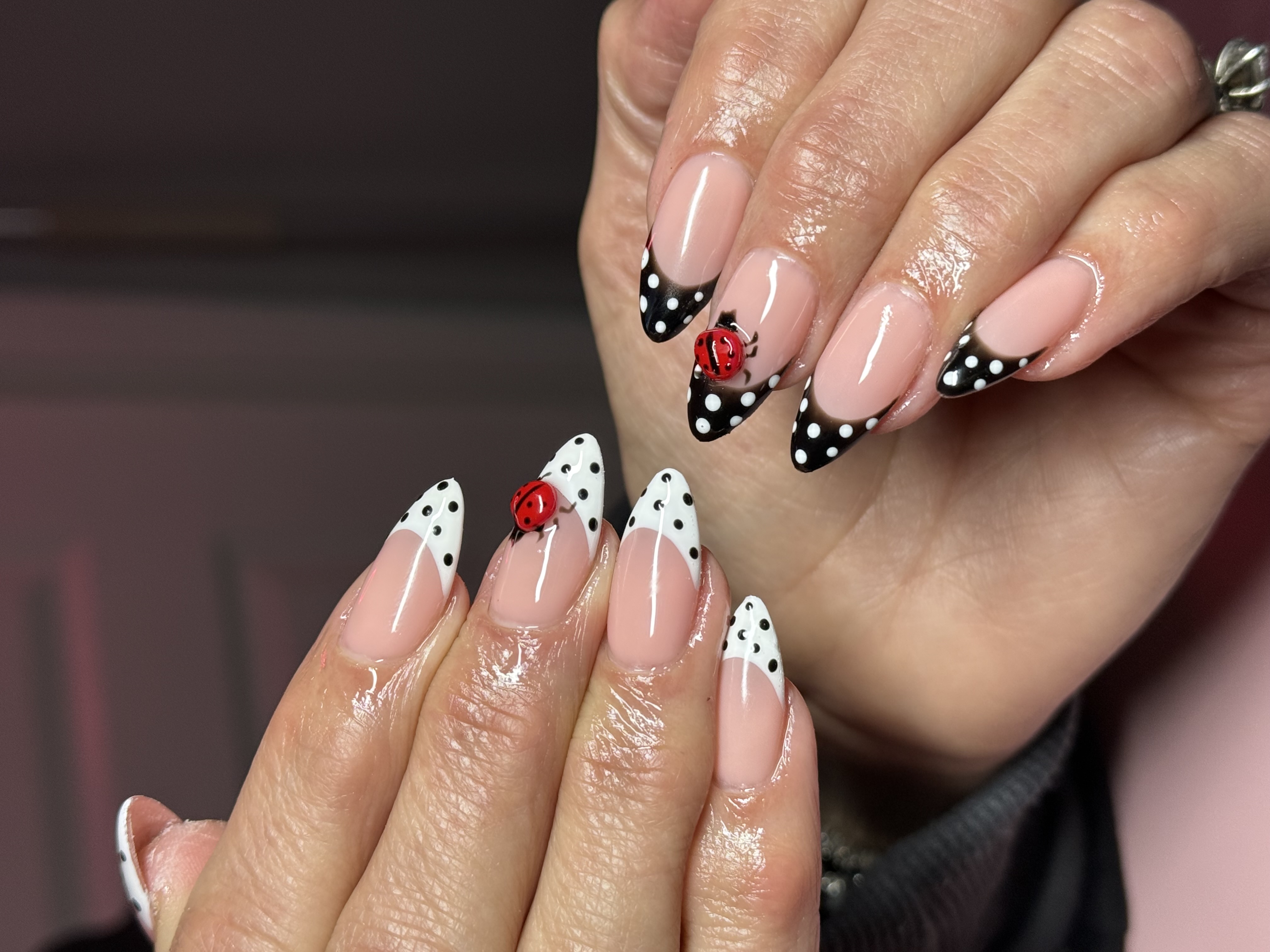 Almond french tip nails with black and white polka dots and realistic 3D sculpted red ladybug charms