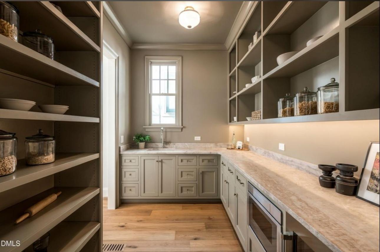 Trending luxury scullery and back kitchen with custom floor-to-ceiling open shelving, stone countertops, integrated microwave, prep sink, and under-cabinet illumination