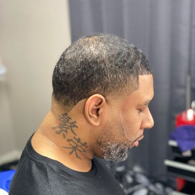 Side profile of a sharp taper haircut with trimmed beard and crisp hairline
