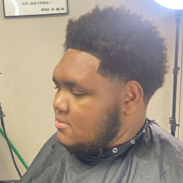 Textured afro taper fade with sharp hairline and clean beard transition