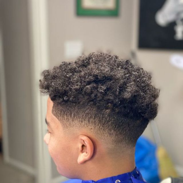 High-top curly fade with razor-crisp hairline and clean neckline taper