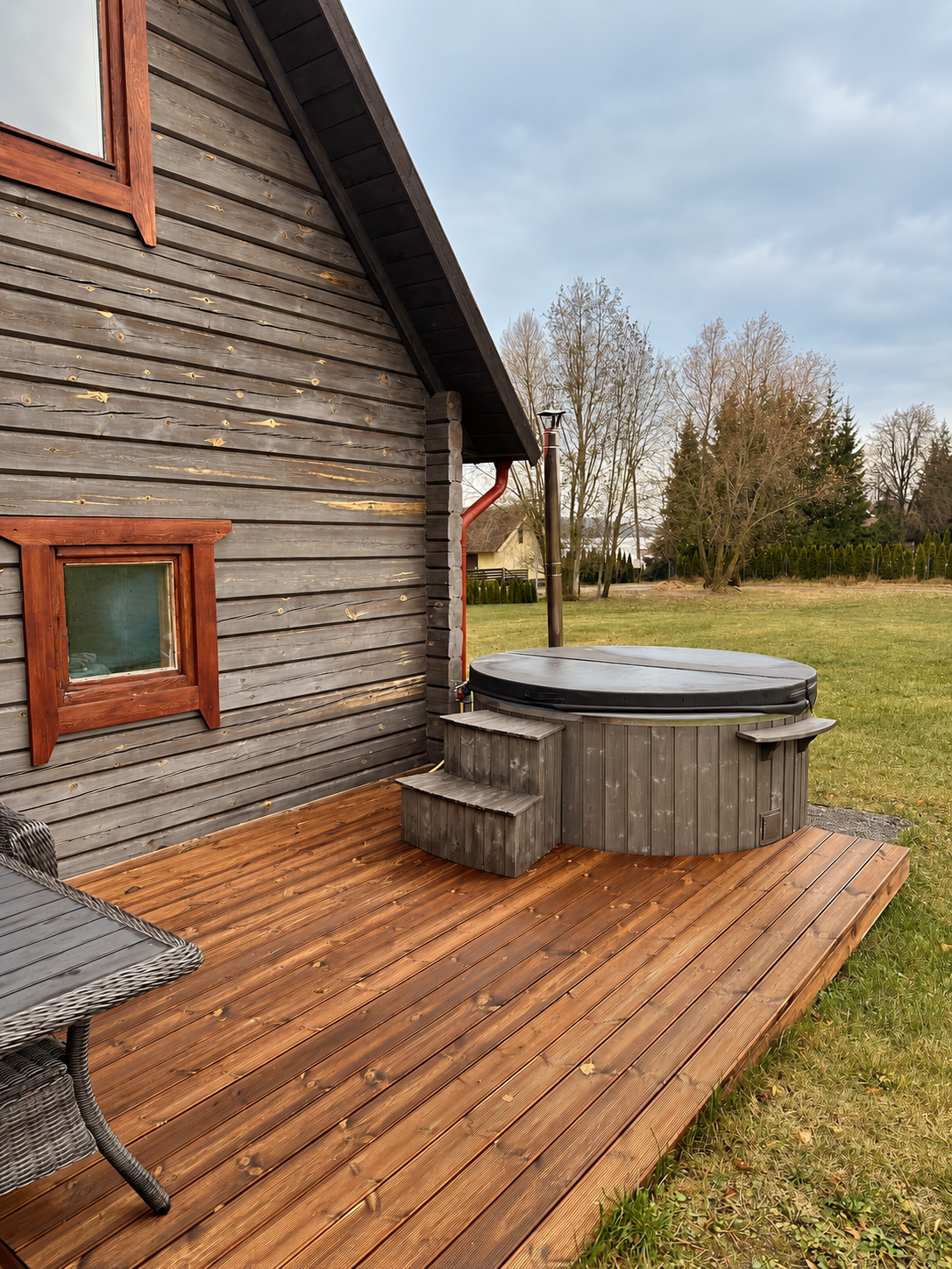 Cedar deck beside the family log cabin with a round wood-fired tub