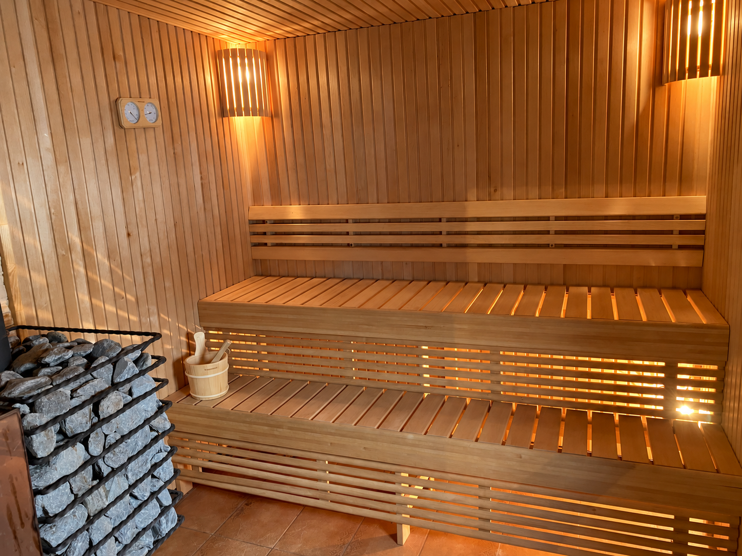 My summer house sauna with tiered wooden benches, warm lighting, stones and bucket