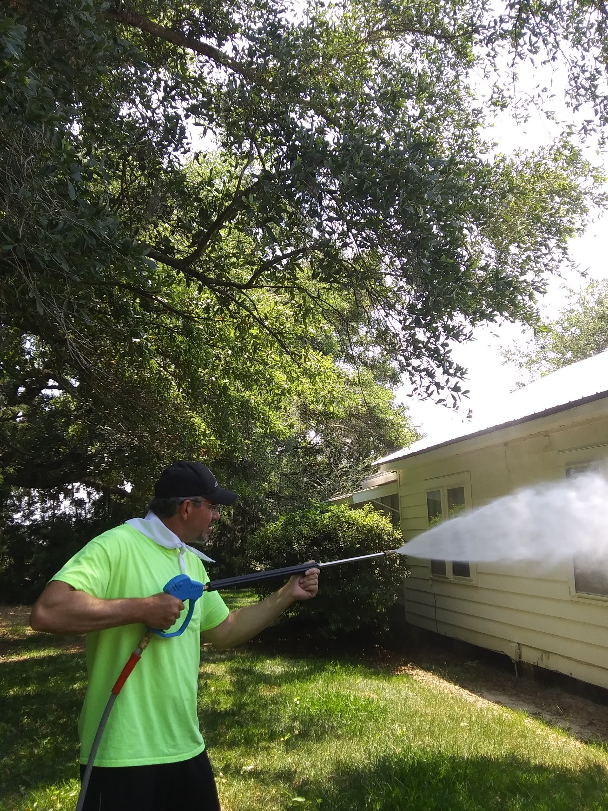 Mr Power Clean Pressure Washing owner washing residential house siding under trees in South Georgia