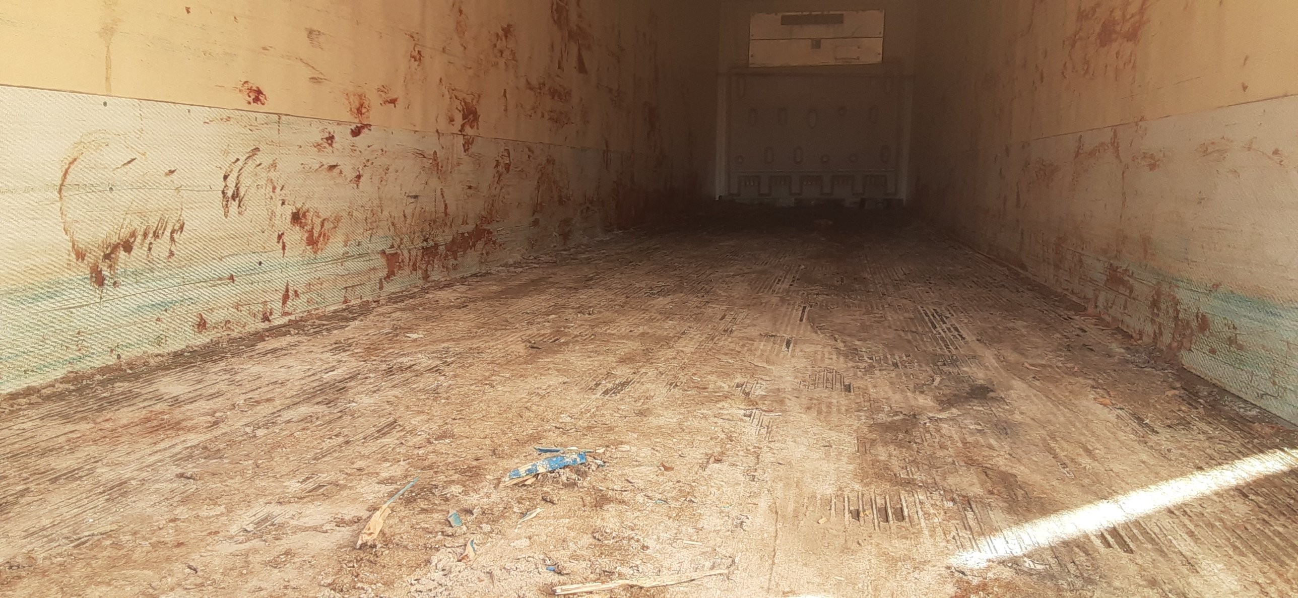 Refrigerated cargo trailer interior with heavy mud and residue before pressure washing