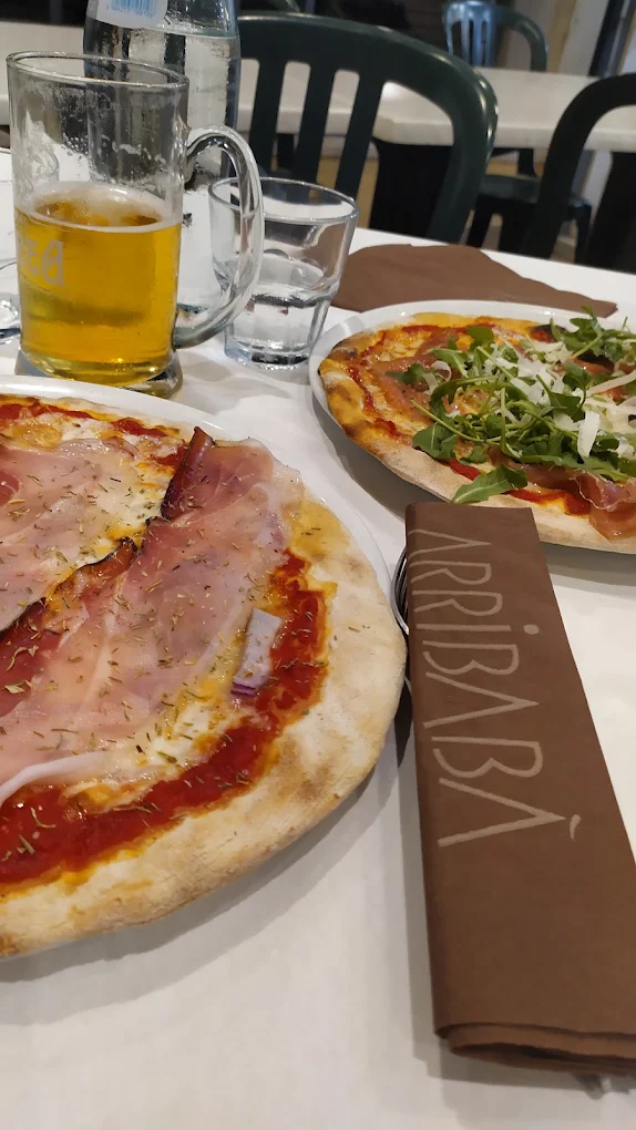 Tavolo reale di Arribabà a Sarzana con pizze sottili appena sfornate, birra e tovagliolo ufficiale