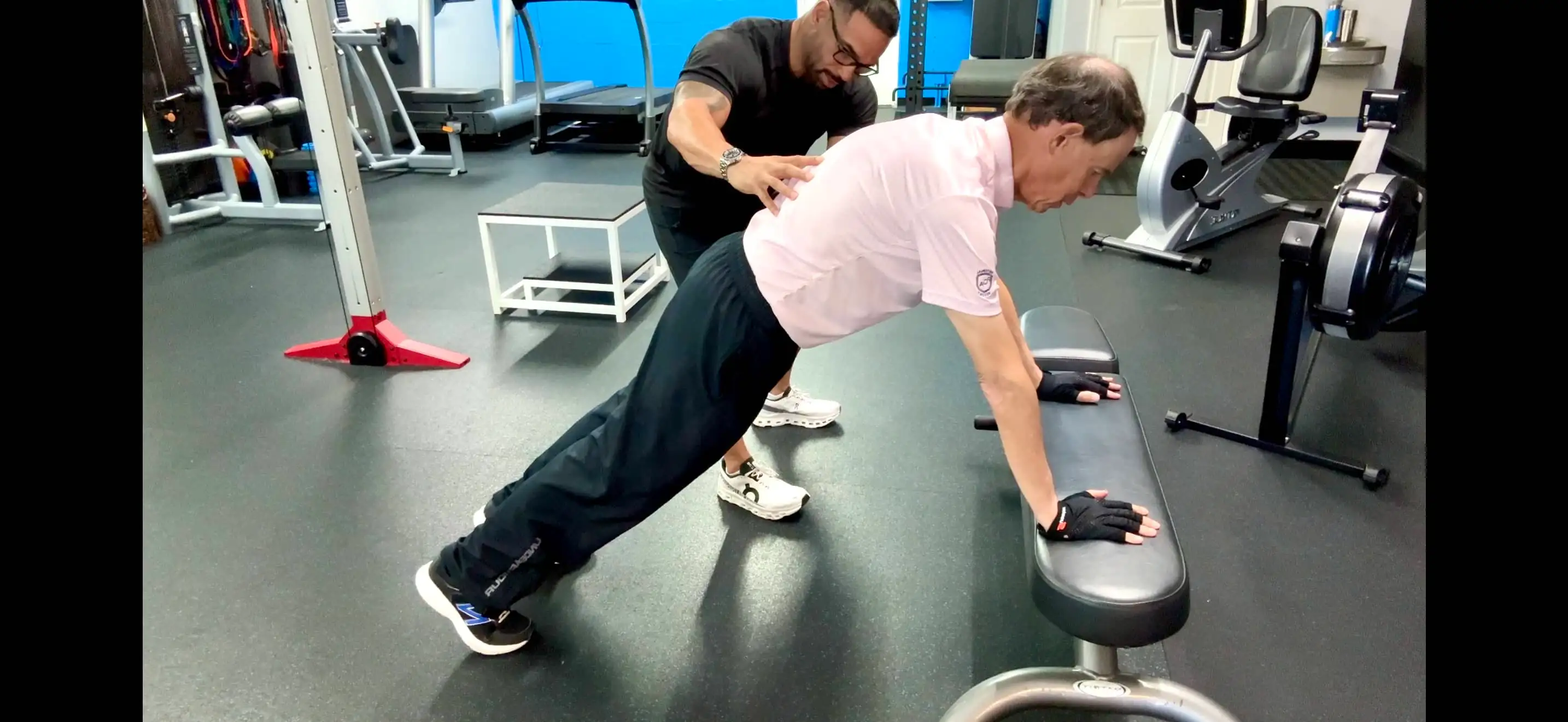 Coach CC Matthews coaching an older adult client through incline plank form in the gym