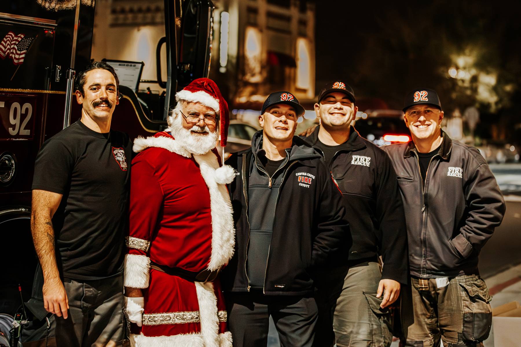 Santa Claus posing with local firefighters beside the fire truck at Skate Night
