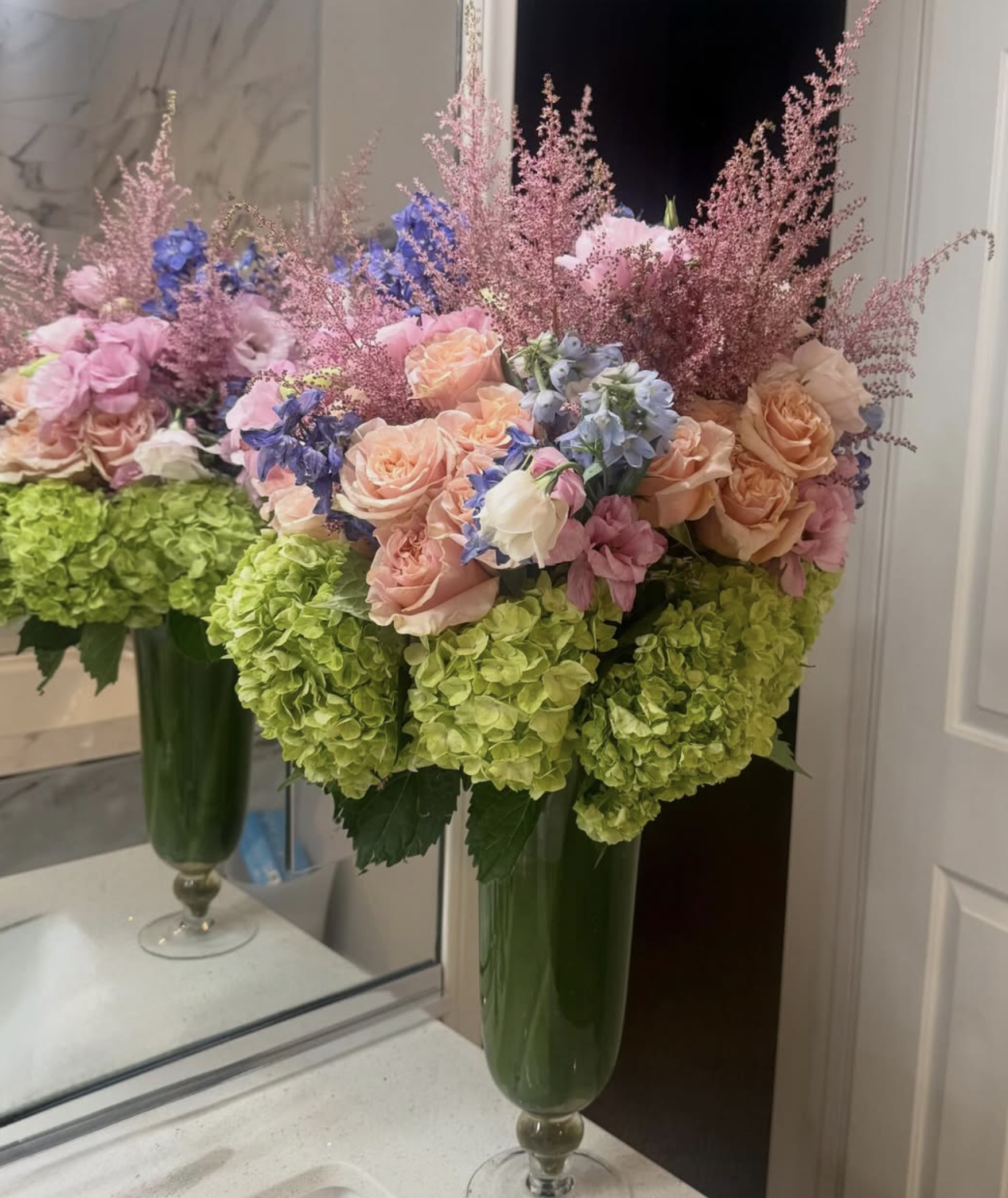 Tall floral arrangement featuring peach roses, hydrangea and seasonal greenery designed by Creative Floral Designs
