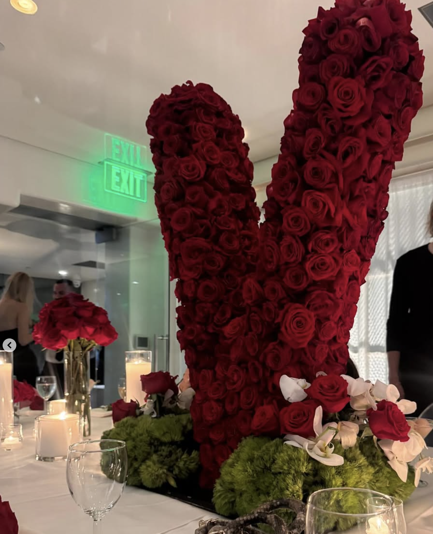 Grand sculptural monogram centerpiece crafted with dense red roses and lush green moss
