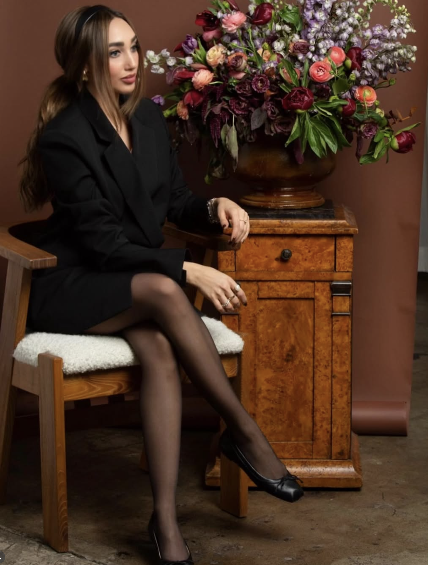 Creative Director beside a grand classical urn arrangement of deep plum and autumn florals