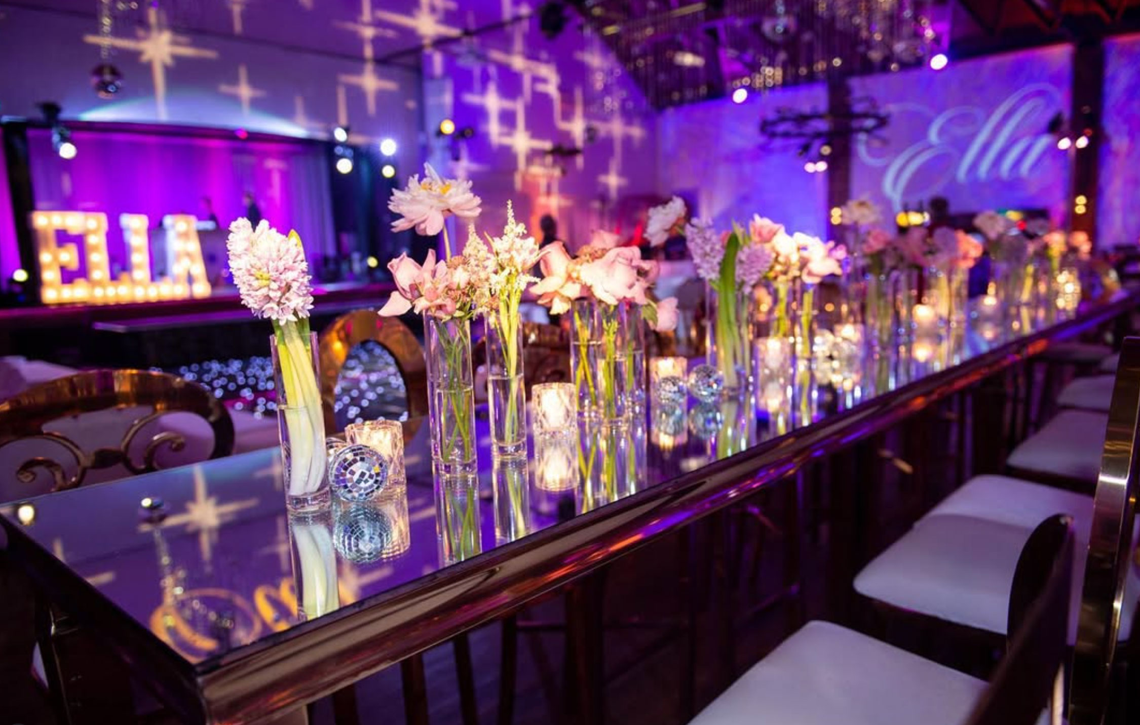 Mirrored celebration banquet table with glowing candles and floral arrangements