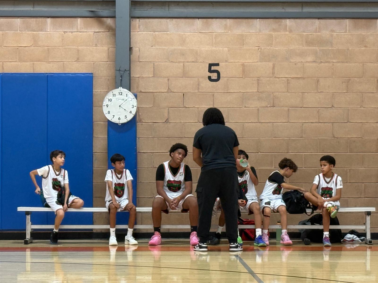 Purpose Driven Hoops coach talking with players on the court bench